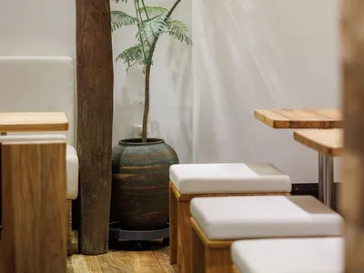 A modern, minimalist restaurant with wood and concrete furniture and a leather padded lounge.