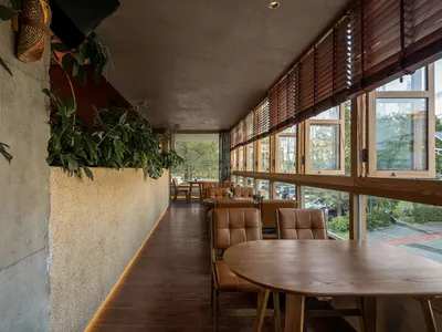 Industrial-style restaurant interior with wooden furniture and greenery.