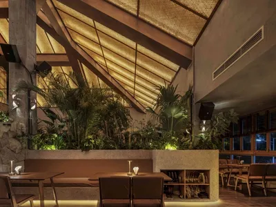 A modern restaurant interior featuring wood, concrete, and plaster materials.