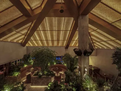 An industrial-style restaurant interior with wooden beams and foliage.