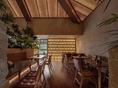 Industrial-style restaurant interior with wooden tables, concrete walls, and fabric seating