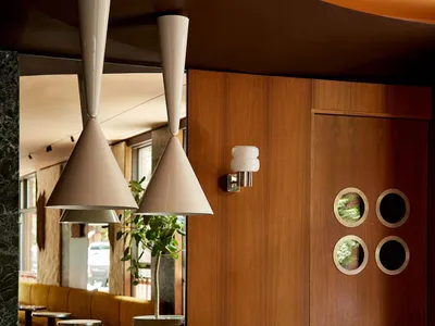 A modern interior design of a restaurant bar with a wooden counter, marble surface, and concrete and wooden elements.