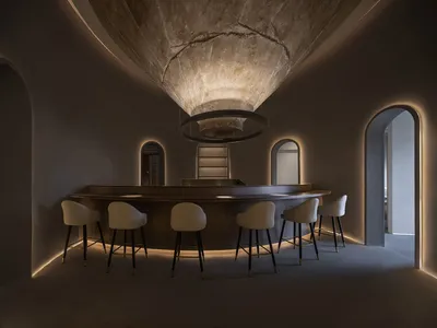 A modern restaurant bar counter made of concrete with white chairs.