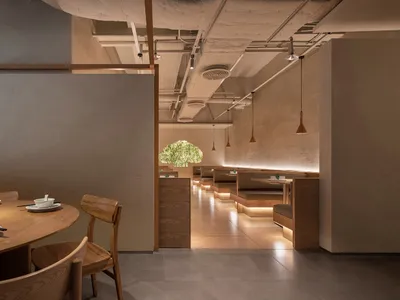 A modern restaurant interior featuring wooden tables and chairs, contemporary lighting, and a minimalist design aesthetic.