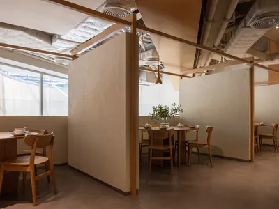 Modern restaurant with wood interior design, featuring tables and chairs.
