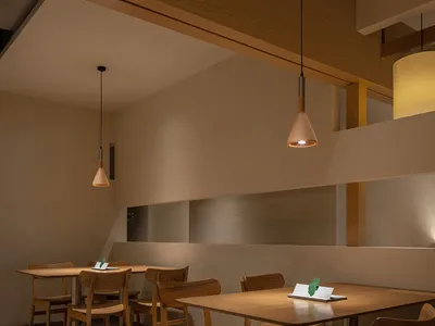 A modern restaurant interior features wooden tables and chairs.