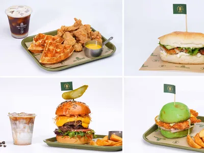 A food tray containing various food items such as fried chicken, waffles, a burger, fries, and an iced coffee drink.