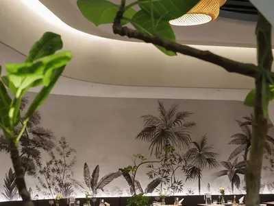 Lushly decorated cafe with wooden furniture and plant life on tables and walls.
