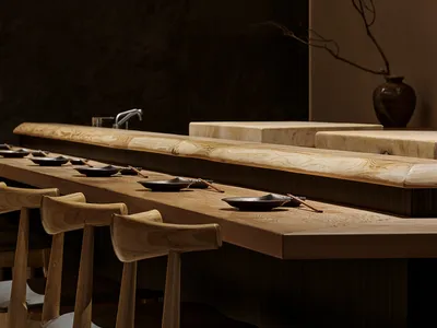 A modern restaurant bar featuring wooden furniture and minimalistic design elements.