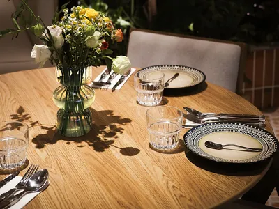 A table set for dining in a modern restaurant, featuring wooden elements and a vase of flowers.