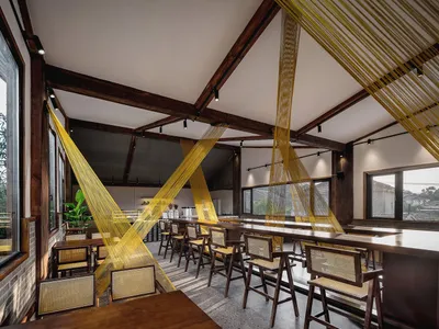 A modern cafe interior with wooden tables and chairs, hanging yellow threads, and large windows