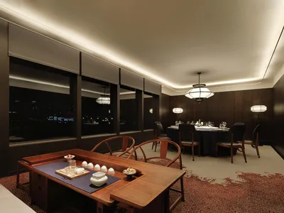 A well-lit, modern restaurant dining area featuring wooden furniture and a cozy atmosphere with large windows overlooking the