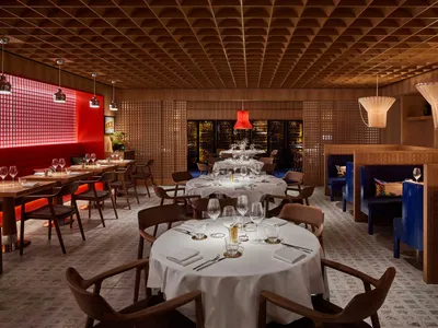 A modern restaurant interior with wooden tables, chairs, and walls.