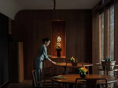 A minimalist restaurant interior with dark wood furniture and a warm, inviting atmosphere.
