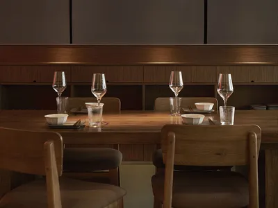 A rustic, industrial-themed restaurant interior with wood furniture, metal accents, and dark, dramatic lighting.