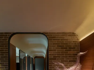 Modern hotel corridor with minimalist design featuring brick, concrete, and wood materials.
