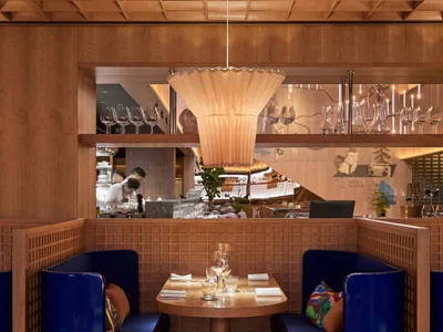 A cozy restaurant interior with modern blue booths and wooden accents.