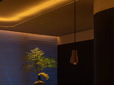 A modern restaurant interior with wooden furniture, green plates, and a vase with flowers on a table.