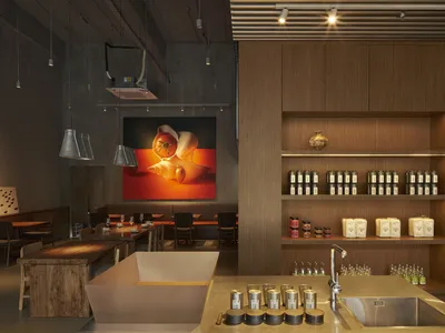 Modern restaurant interior featuring wooden tables and shelves with a variety of products.