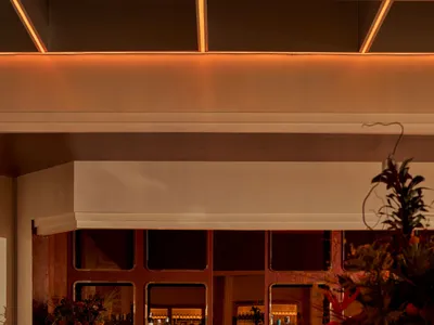 A modern restaurant bar with metal tables, leather seating, and walnut accents.