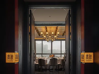 Modern, industrial-themed restaurant interior with marble flooring, large windows overlooking a cityscape, and a warm, inviti