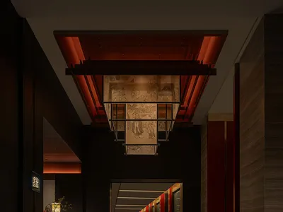 A modern hotel hallway features metallic wood walls and red accent columns.