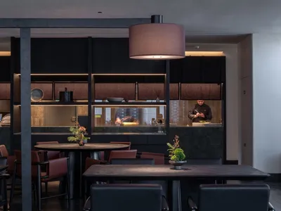 Modern, brightly lit restaurant interior with dark walls and stainless steel accents.