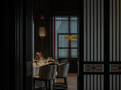 Modern restaurant interior with wooden floors, glass walls, and fabric curtains.