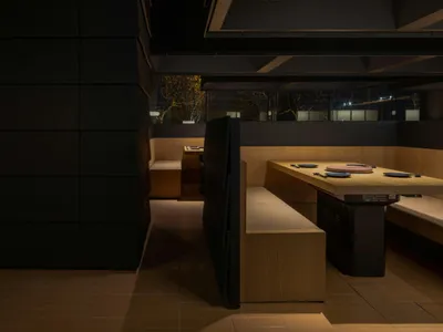 暗黑極簡餐廳室內，搭配木質座椅與燈光照明。