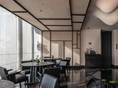Modern restaurant interior featuring concrete and glass materials with black accents and minimalist design.