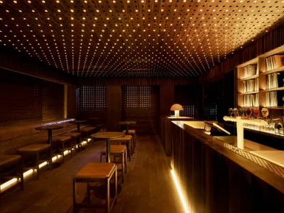 A dimly lit restaurant bar with a barrel backdrop featuring a wooden ceiling and decor.