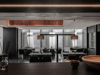 Modern restaurant interior with concrete floor, wooden accents, and glass partitions.