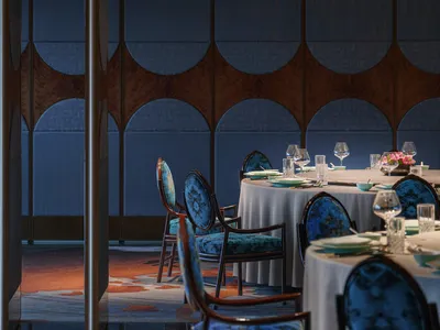 A modern restaurant interior with blue upholstered chairs and textured fabric walls