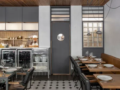 Industrial-style restaurant interior featuring metal cabinets, glass walls, and concrete floors