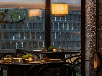 Modern restaurant interior with wooden tables, glass lamps, and fabric pendant lights.