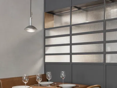 A modern restaurant setting with a table set for dinner, featuring wooden chairs, glass windows, and a leather booth seat.