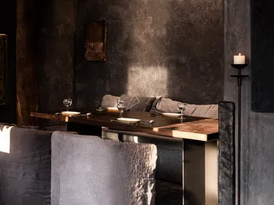 Industrial-themed restaurant interior with metallic table, wooden accents, and textured fabric seating.