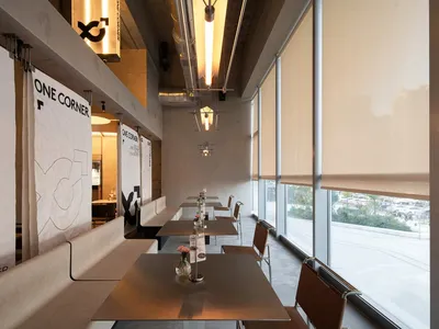 A modern industrial restaurant with metallic furniture, large windows, and minimalist decor.