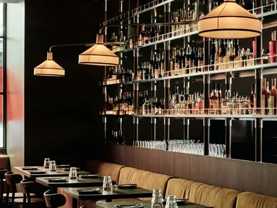 Modern restaurant bar with a metal shelving system displaying an extensive selection of glassware and bottles.