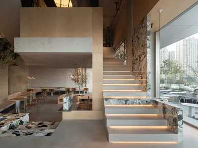Modern restaurant interior with concrete walls, marble countertops, and bamboo seating.
