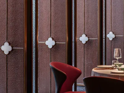 A modern restaurant interior featuring glazed glass panels and a red upholstered chair.