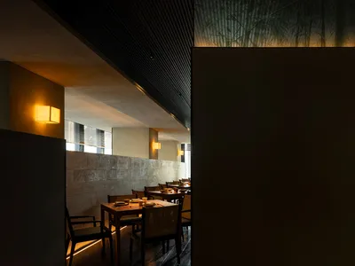 極簡餐廳室內以木質家具搭配混凝土牆面，搭配溫暖燈光與寧靜氛圍。