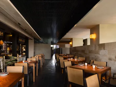 Modern restaurant interior with wooden tables, concrete flooring, and brick accents.