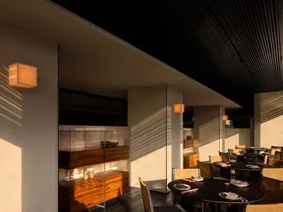 A modern restaurant interior featuring wooden elements such as tables, chairs, and a cabinet.