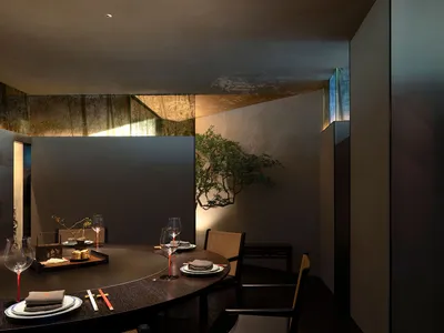 Circular dining table surrounded by chairs in a minimalist restaurant setting.