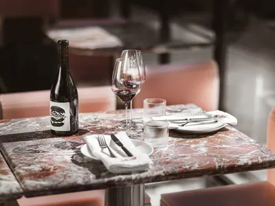 Marble countertop in an industrial-style restaurant with wine glasses, a wine bottle, and tableware.