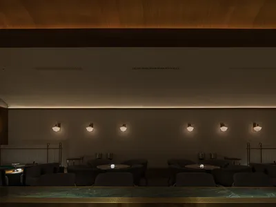 A modern restaurant bar with concrete walls and lighting fixtures.