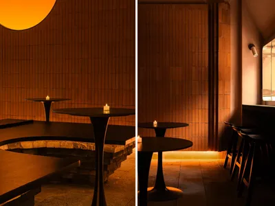 Photo of a modern restaurant interior with brick walls and candlelit tables.