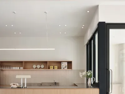 A modern minimalist kitchen featuring light-colored wooden cabinets and a tiled backsplash.