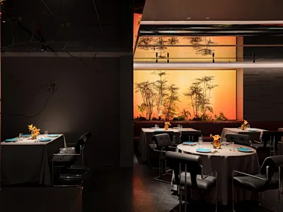 A photograph of a modern restaurant interior with concrete, bamboo, and glass materials.